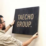 Laser etched black wood sign for Taecho Group