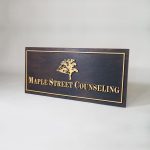 Maple Street Counseling Gold artwork on torched wood