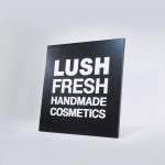 Lush hanging retail blade sign in black stained wood with raised dimensional white letters