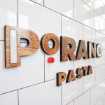 Porano Pasta dark wood and colored wood restaurant wall sign on white tile