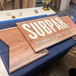 subpar mini golf cedar and white wood ribbon sign