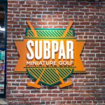 Subpar Mini Golf colorful painted sign on brick wall