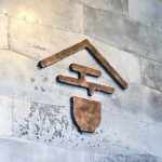 Rustic, torched wood illuminated sign on metal wall for Asha Tea House, a cafe in Berkeley and San Francisco.