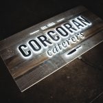 Reclaimed barnwood sign with push-through illuminated lettering for Corcoran Caterers, an event catering company serving the Washington DC area.