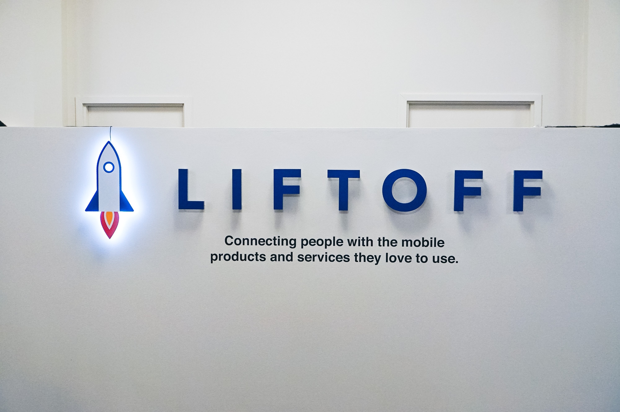 Illuminated rocket logo sign for Liftoff, a company that creates a mobile app optimization marketing platform. Office designed by Knotel, an office space rental agency.