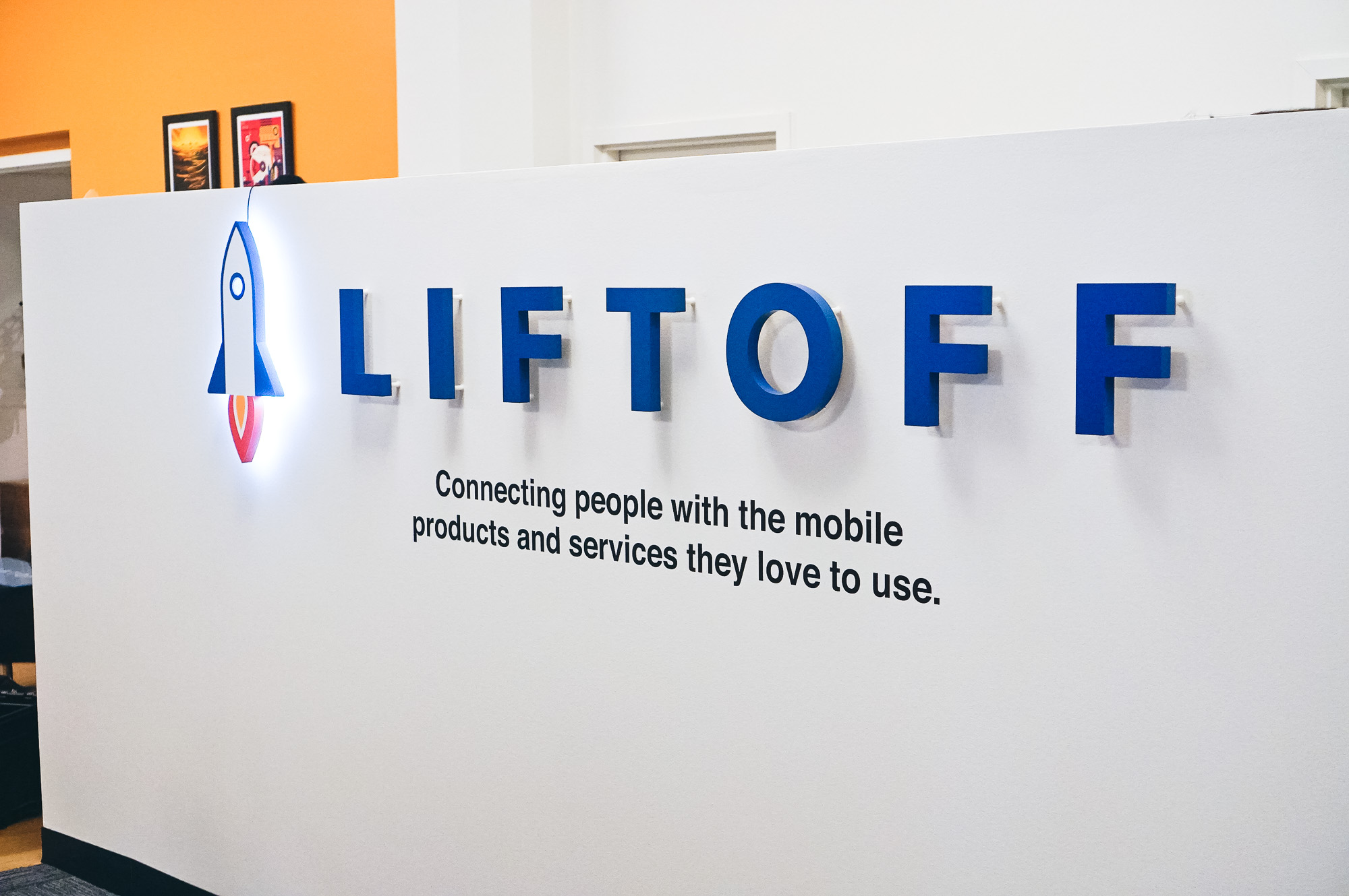 Illuminated rocket logo sign for Liftoff, a company that creates a mobile app optimization marketing platform. Office designed by Knotel, an office space rental agency.