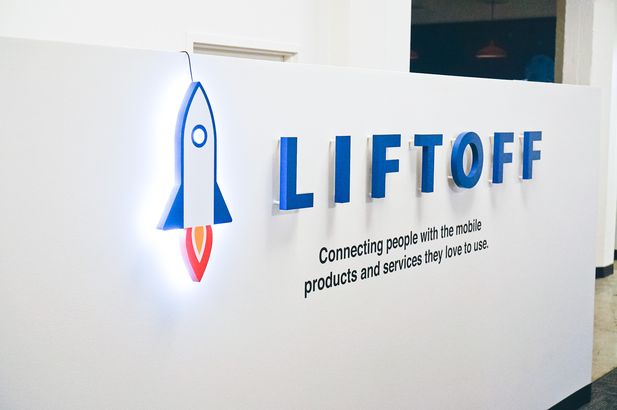 Illuminated rocket logo sign for Liftoff, a company that creates a mobile app optimization marketing platform. Office designed by Knotel, an office space rental agency.