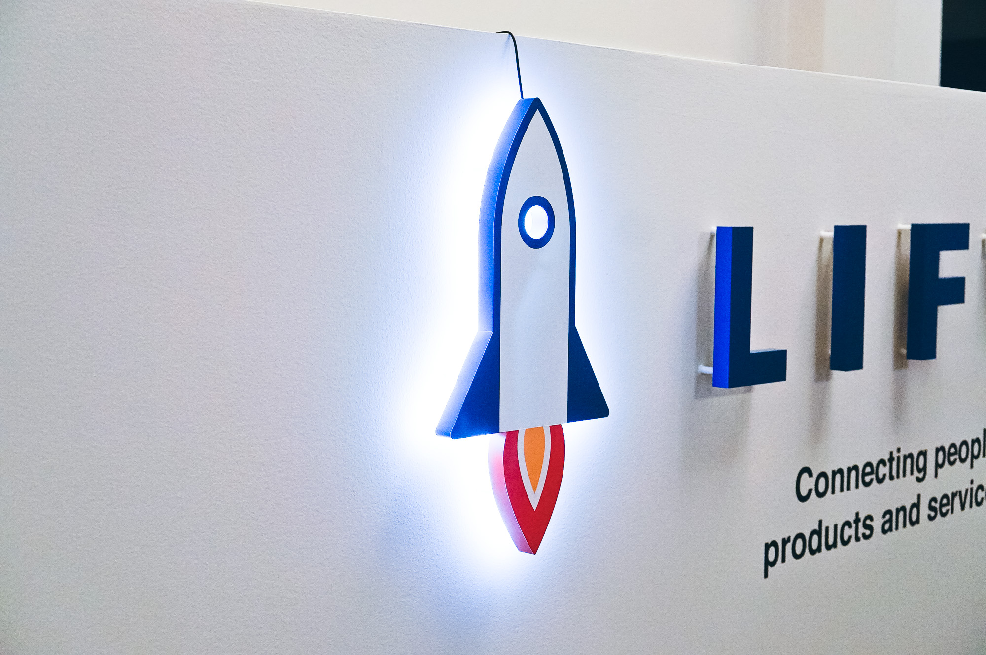 Illuminated rocket logo sign for Liftoff, a company that creates a mobile app optimization marketing platform. Office designed by Knotel, an office space rental agency.
