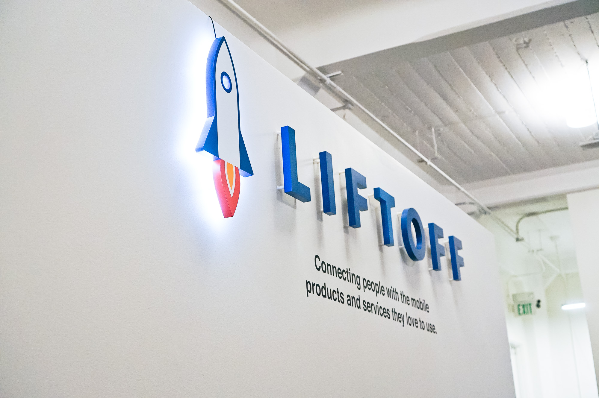 Illuminated rocket logo sign for Liftoff, a company that creates a mobile app optimization marketing platform. Office designed by Knotel, an office space rental agency.