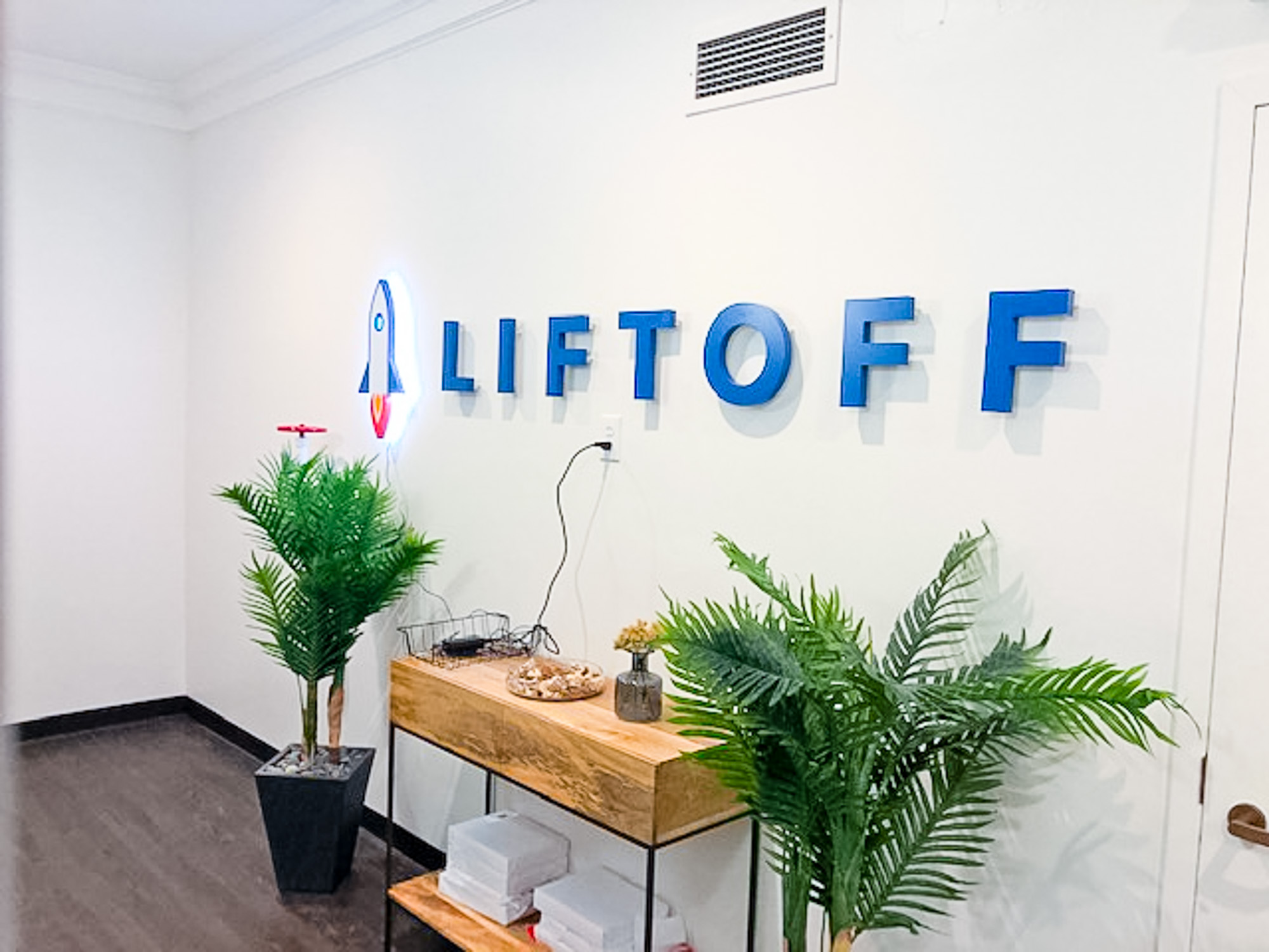 Illuminated rocket logo sign for Liftoff, a company that creates a mobile app optimization marketing platform. Office designed by Knotel, an office space rental agency.
