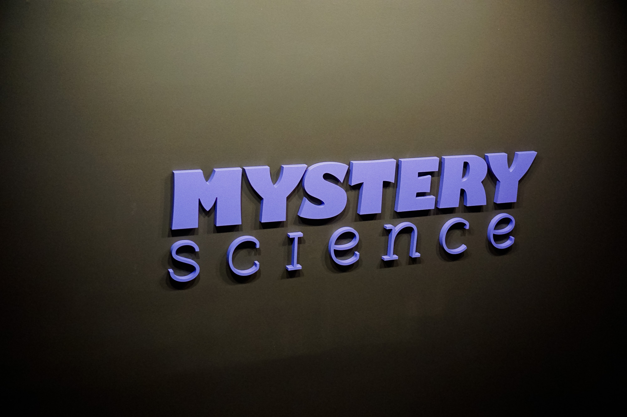 Purple letters on dark grey wall for the Knotel designed Mystery Science lobby, a company that provides open-and-go lessons that inspire kids to love science.