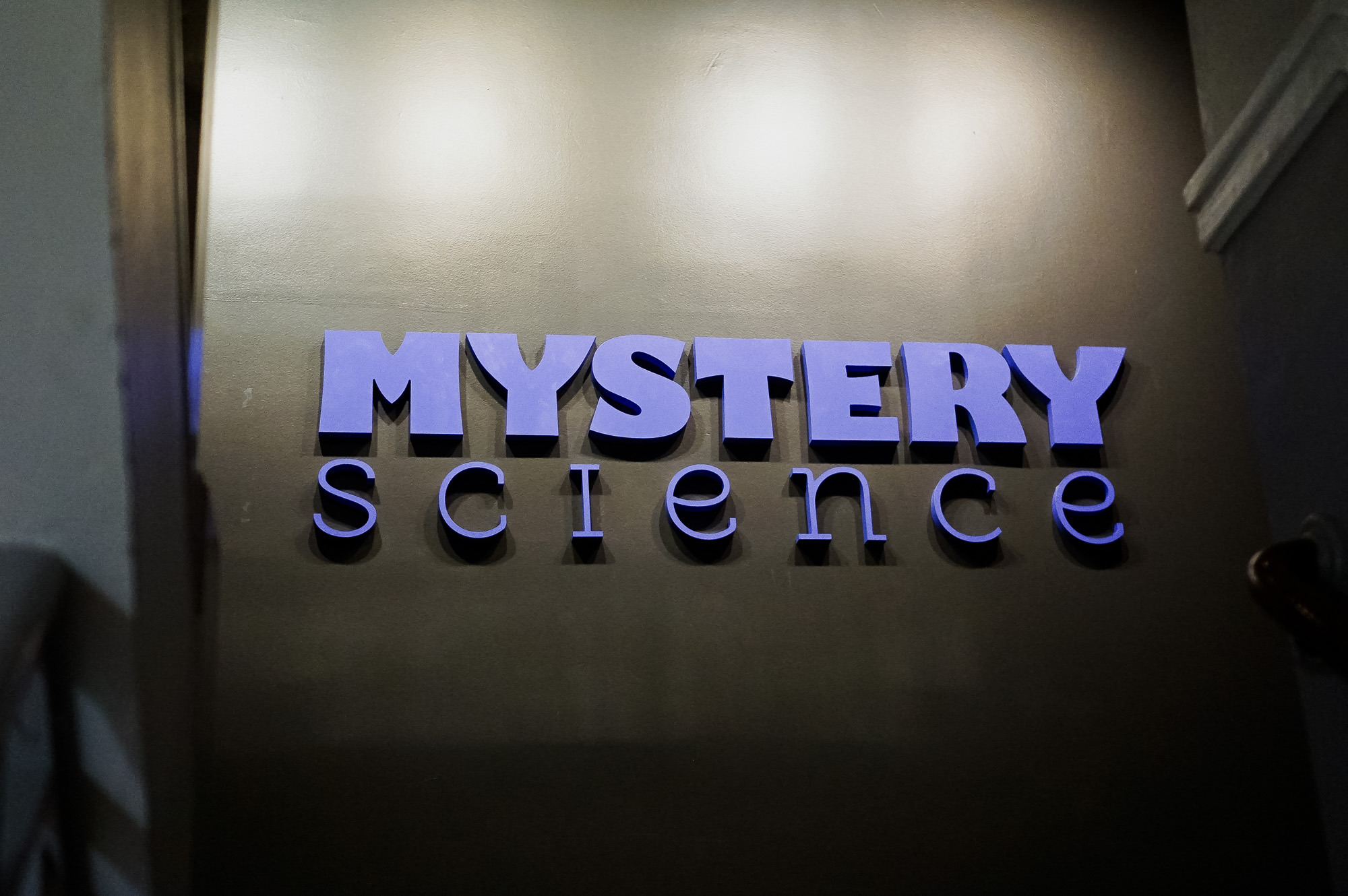 Purple letters on dark grey wall for the Knotel designed Mystery Science lobby, a company that provides open-and-go lessons that inspire kids to love science.