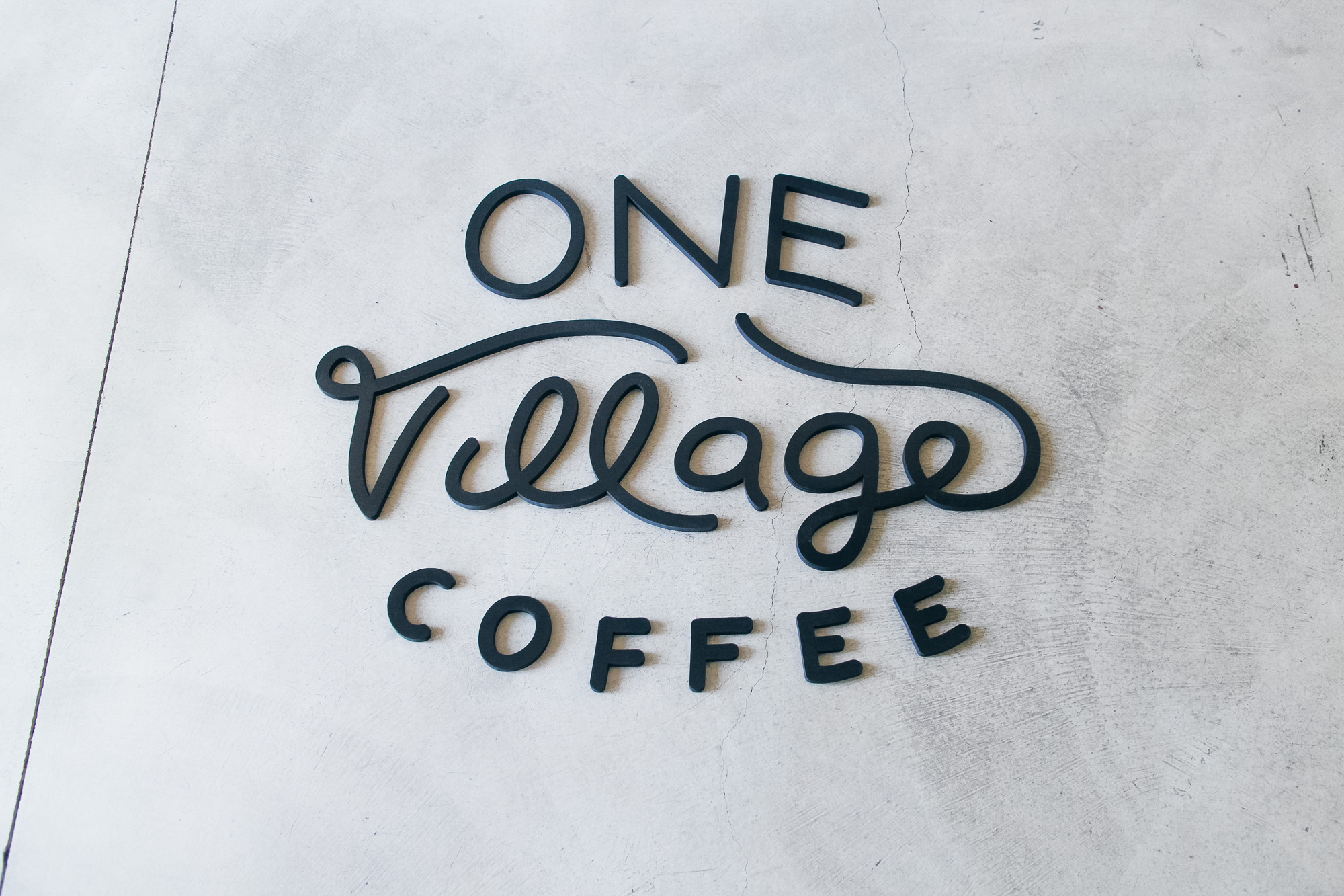 Black script sign for One Village Coffee, a specialty coffee roaster based in Souderton, PA. Black script sign for One Village Coffee, a specialty coffee roaster based in Souderton, PA.