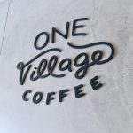 Black script sign for One Village Coffee, a specialty coffee roaster based in Souderton, PA.