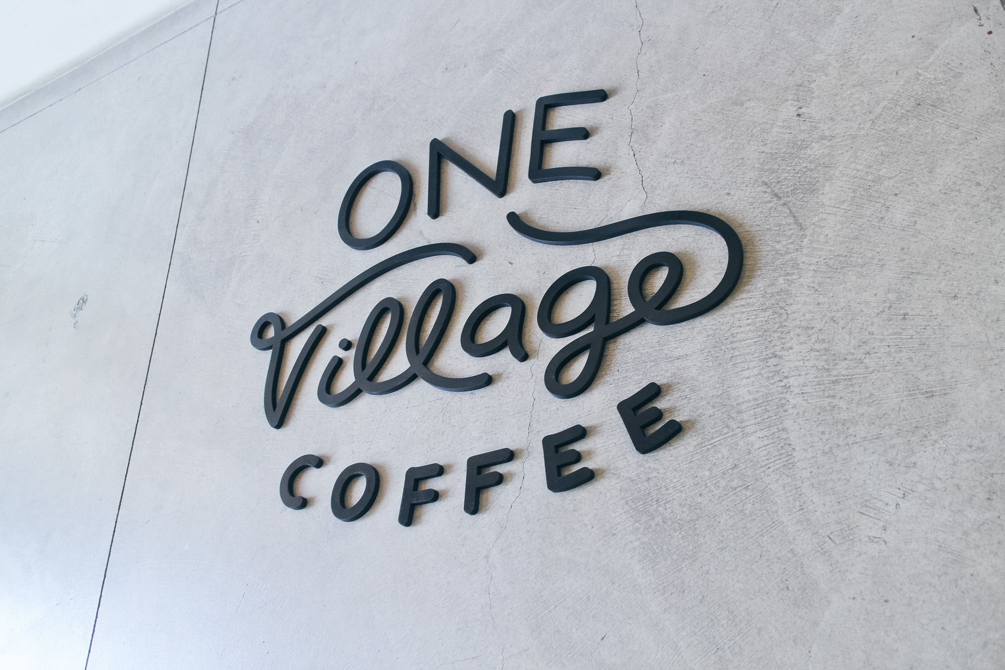 Black script sign for One Village Coffee, a specialty coffee roaster based in Souderton, PA.