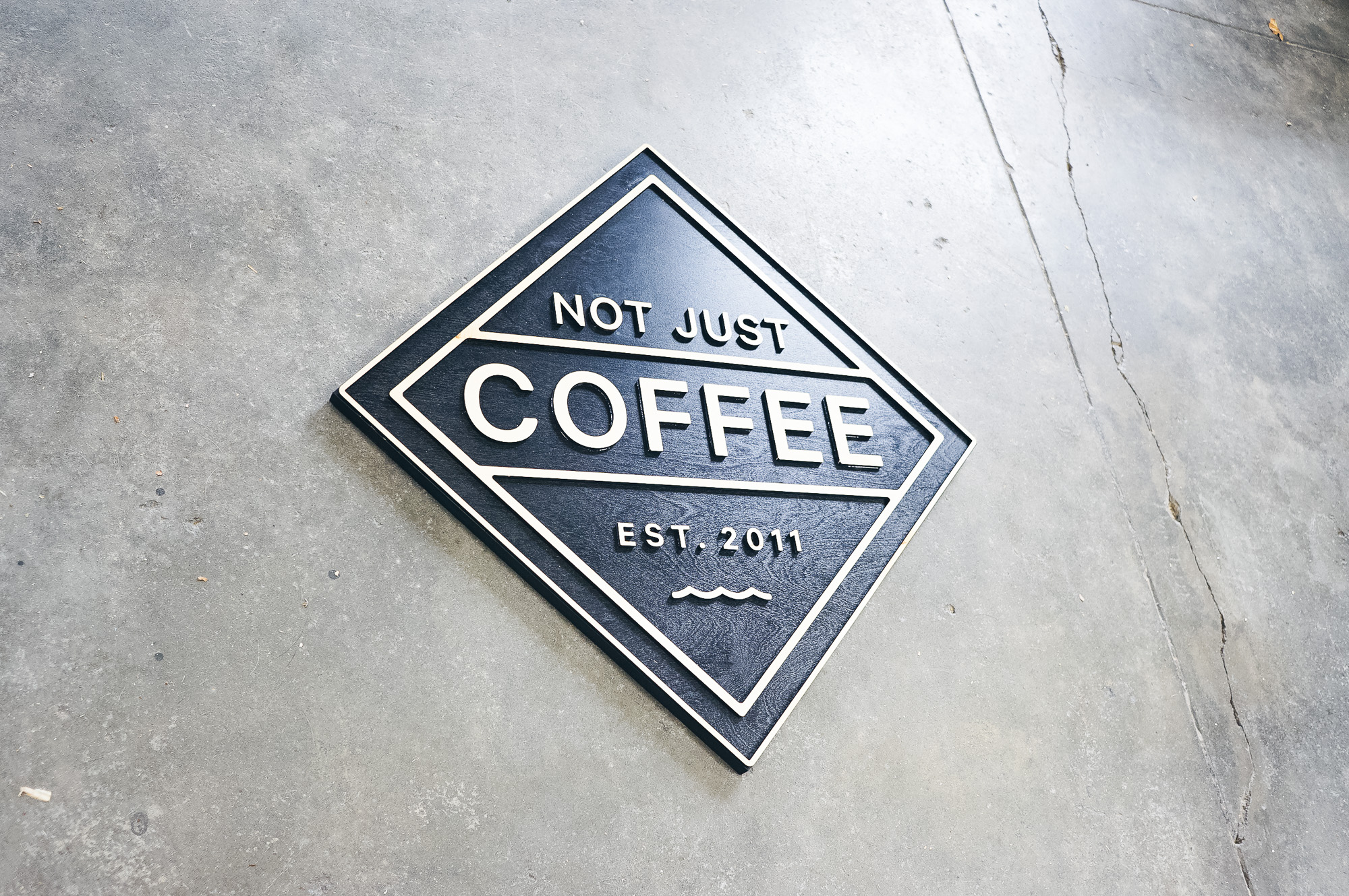 Black and light wood sign for Not Just Coffee