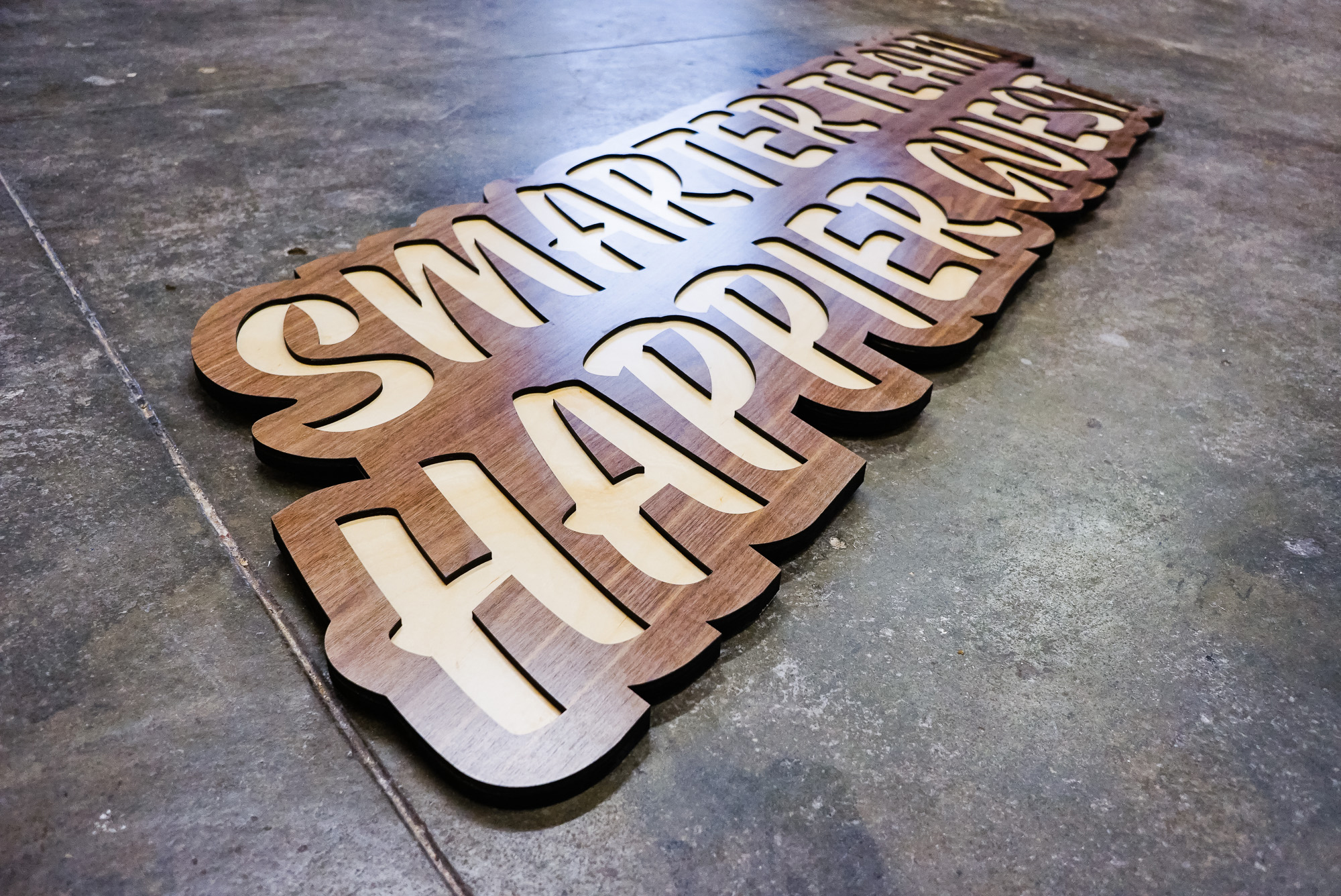 Script wood sign for “Smarter Team, Happier Guest” Quore office. Script wood sign for