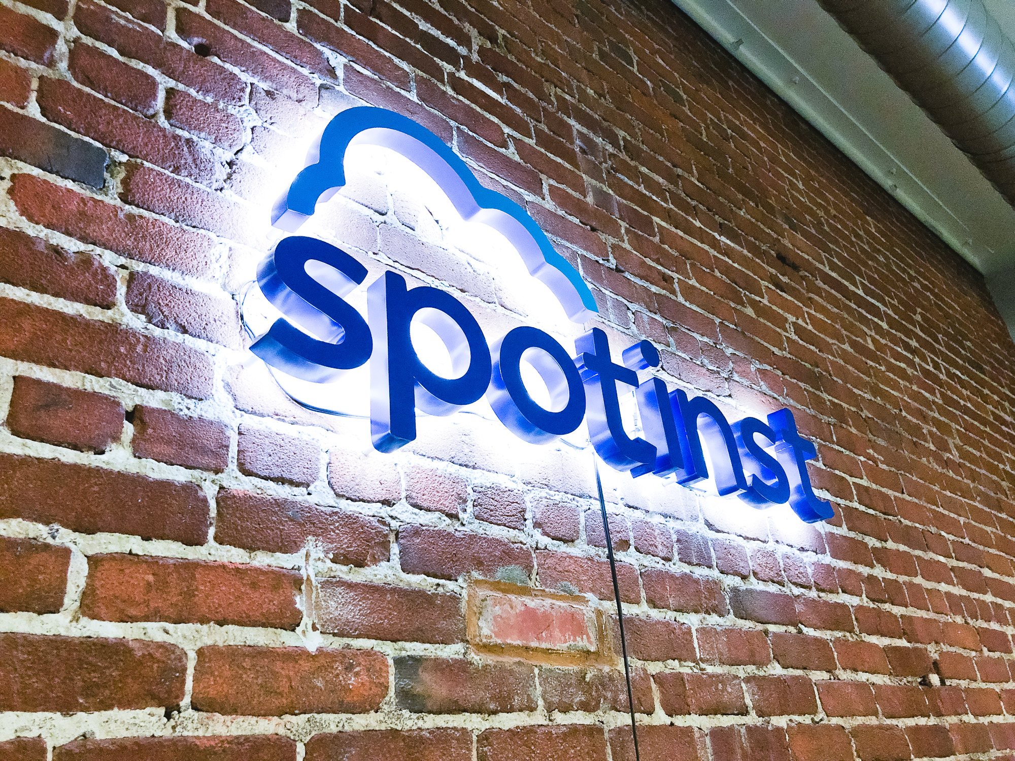 Illuminated, painted blue sign on brick conference room wall for Spotinst, a San Francisco company that creates intelligent workload software.