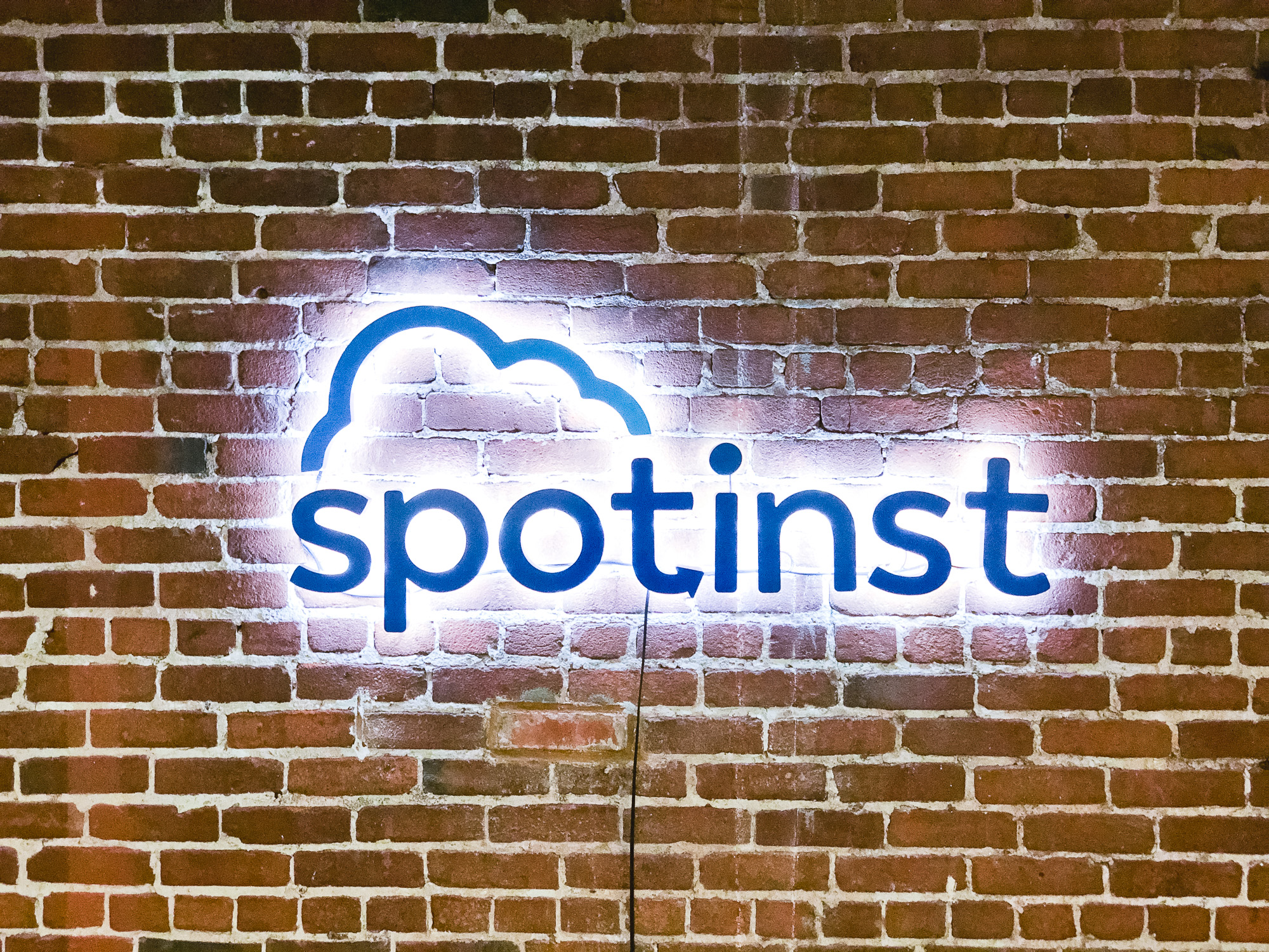 Illuminated, painted blue sign on brick conference room wall for Spotinst, a San Francisco company that creates intelligent workload software.
