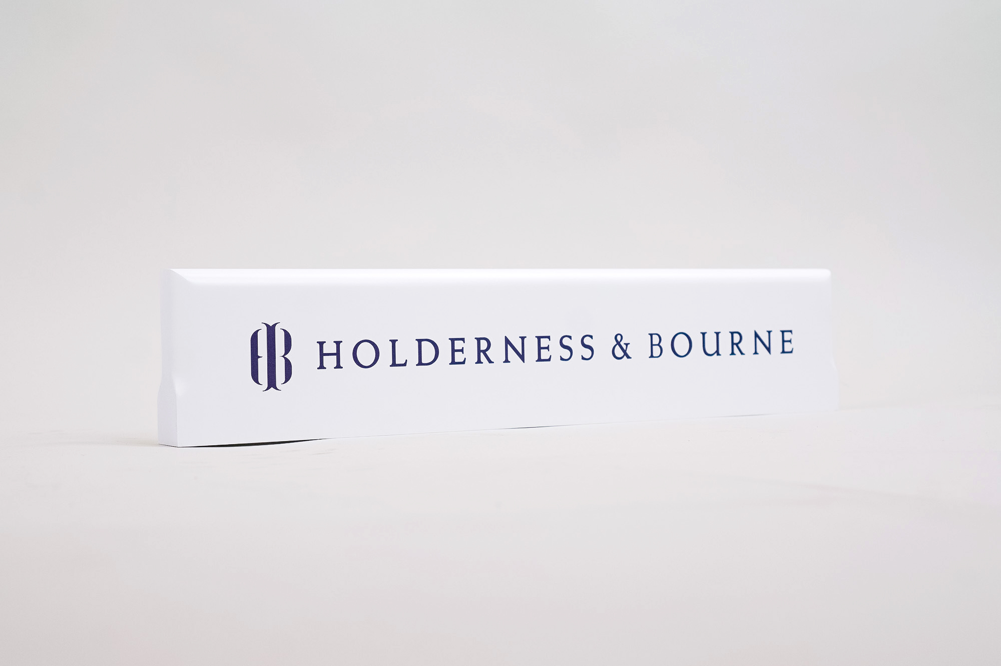 White and navy blue wood retail signs for Holderness & Bourne, a premium golf apparel and accessories company.