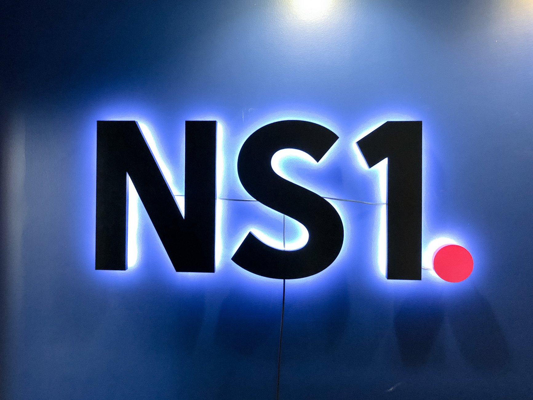 NS1 halo lit sign on dark blue wall NS1 halo lit sign on dark blue wall