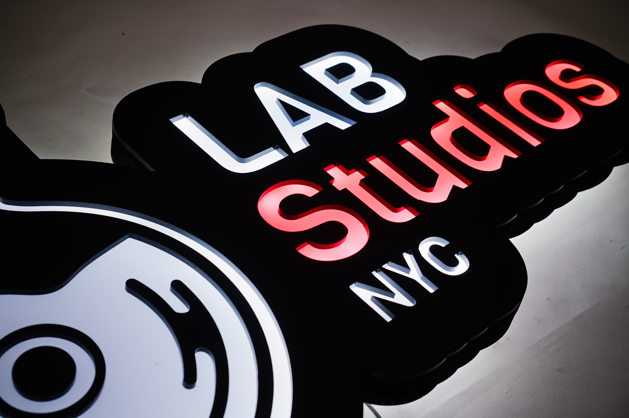 Illuminated pink, white, and black lightbox sign for Lab Studios, a recording studio in New York City.