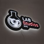 Illuminated pink, white, and black lightbox sign for Lab Studios, a recording studio in New York City.