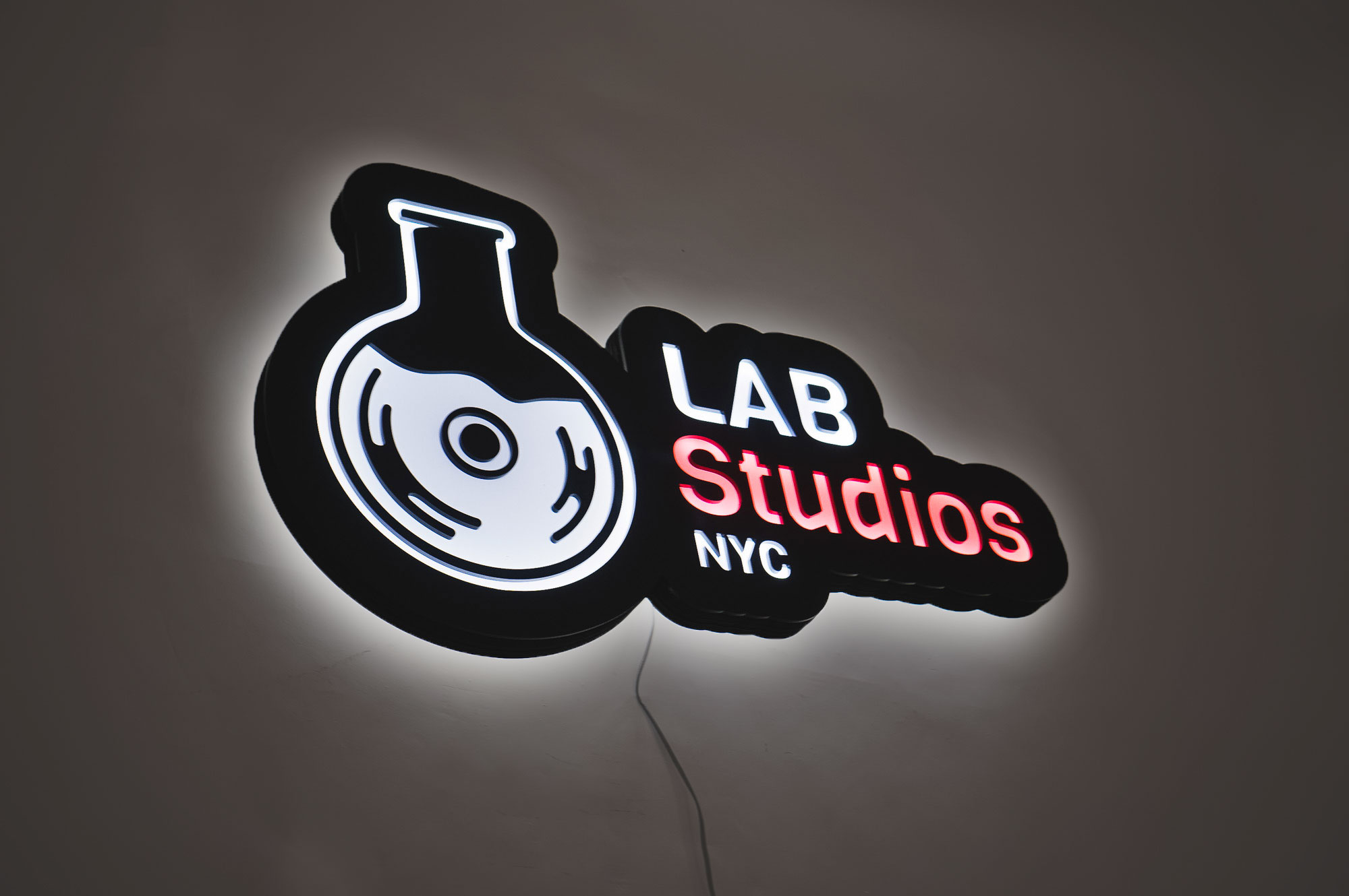 Illuminated pink, white, and black lightbox sign for Lab Studios, a recording studio in New York City.