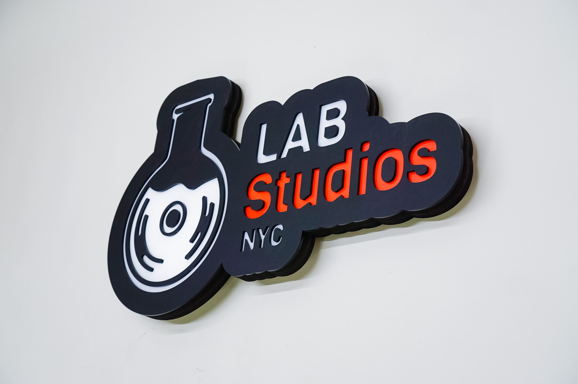 Illuminated pink, white, and black lightbox sign for Lab Studios, a recording studio in New York City.