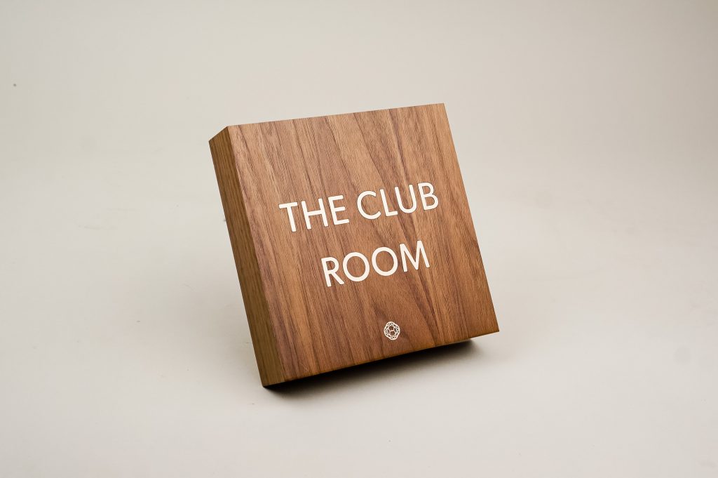 Vintage walnut and inlaid-brass style sign for Nexus Club, a private social and business club in New York.