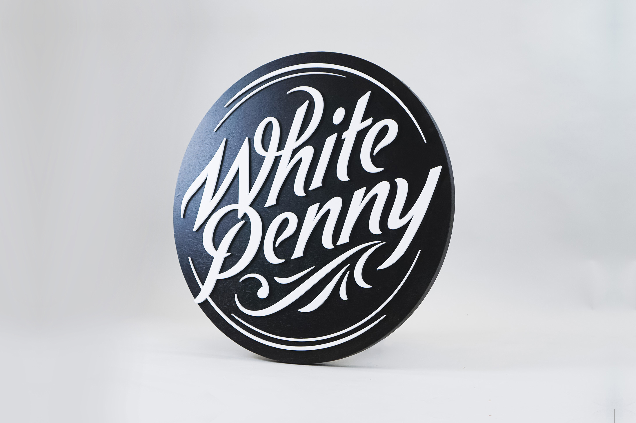 Black and white round raised sign with intricate lettering for Whitepenny, a web development, design and branding firm based in New Jersey. Black and white round raised sign with intricate lettering for Whitepenny, a web development, design and branding firm based in New Jersey.