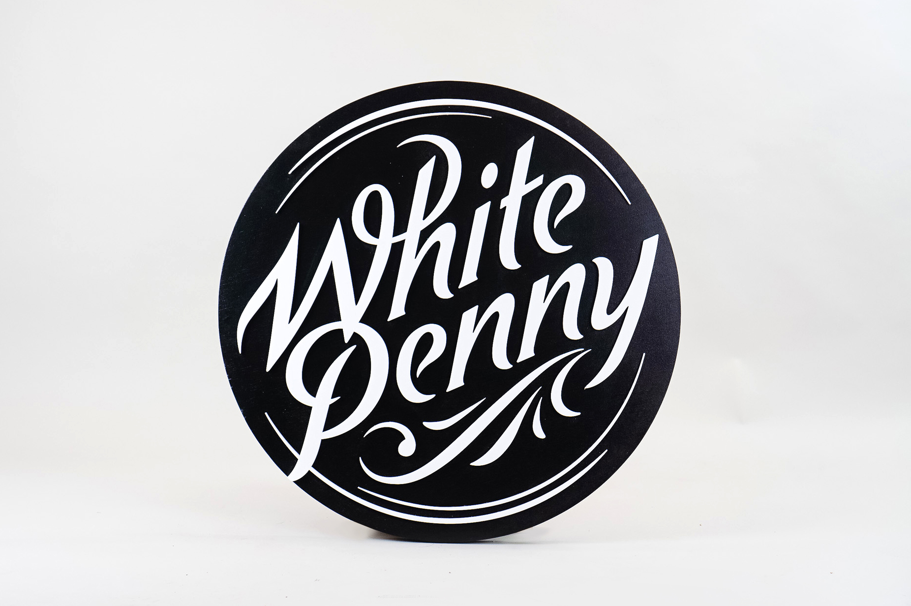 Black and white round raised sign with intricate lettering for Whitepenny, a web development, design and branding firm based in New Jersey.