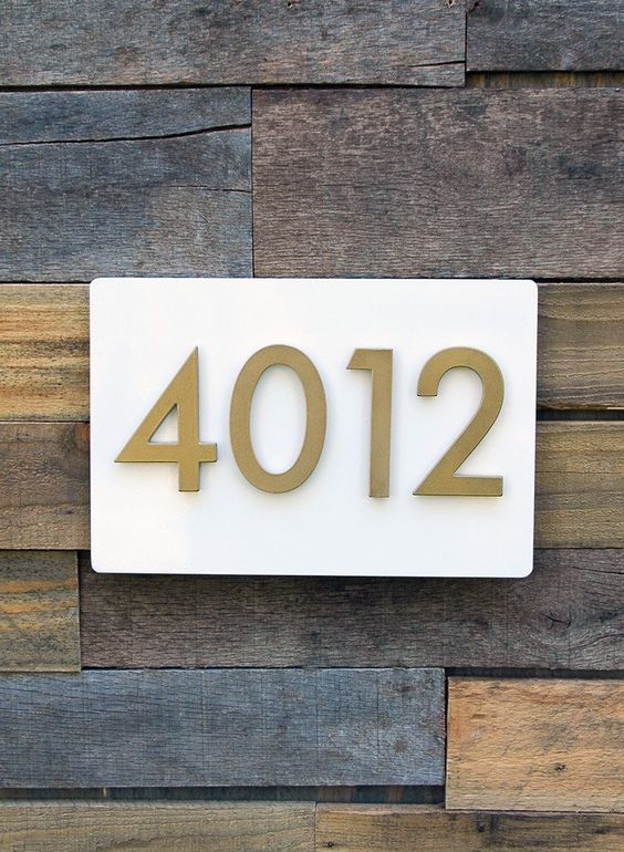 brass house numbers on white panel on reclaimed wood
