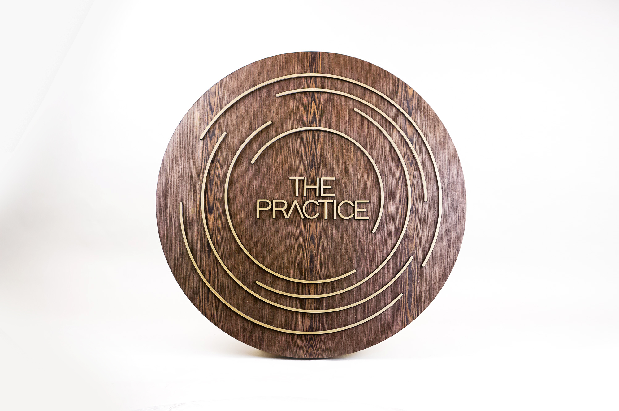 Illuminated dark wood and brass sign for The Practice, a yoga studio at Newtown Athletic Club, a premiere family fitness and wellness center serving residents of Newtown, PA Illuminated dark wood and brass sign for The Practice, a yoga studio at Newtown Athletic Club, a premiere family fitness and wellness center serving residents of Newtown, PA