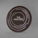 Illuminated dark wood and brass sign for The Practice, a yoga studio at Newtown Athletic Club, a premiere family fitness and wellness center serving residents of Newtown, PA