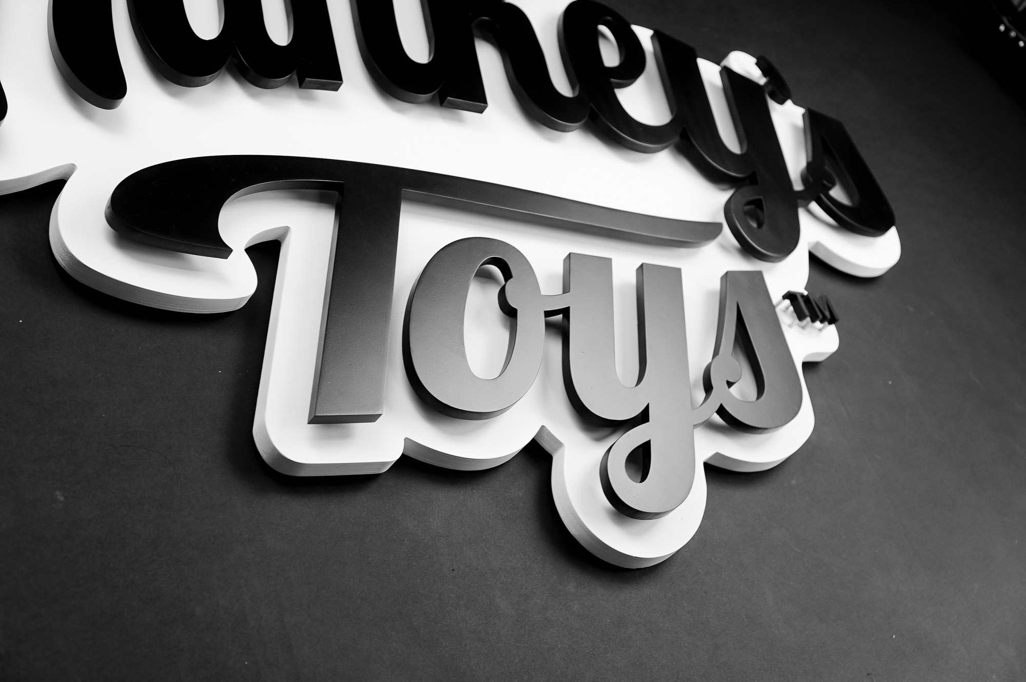 Black and white raised cutout script logo for Mr. Hankey's Toys, maker of handmade adult sex toys.