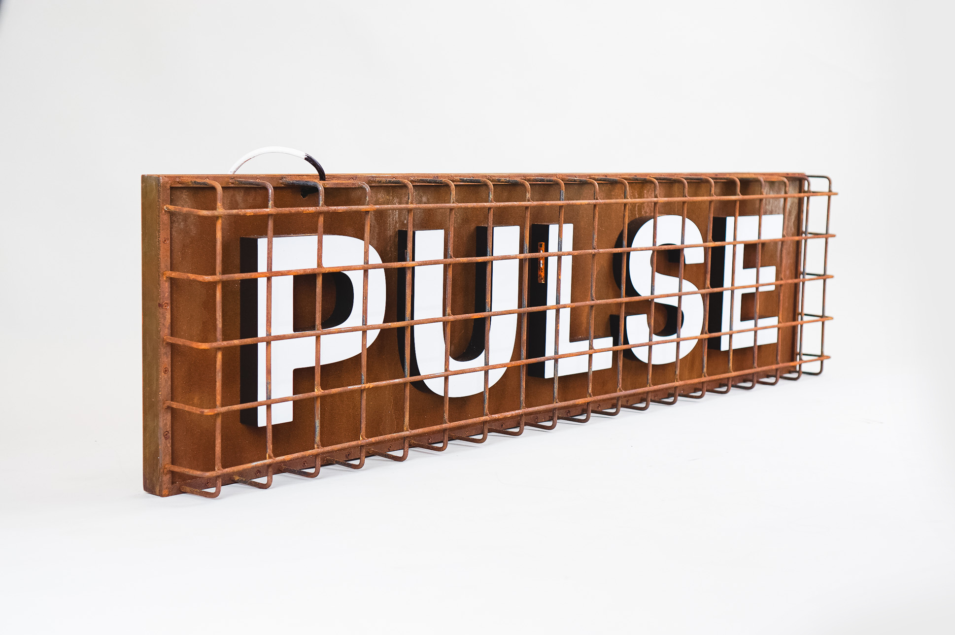 Industrial, caged, rusty metal illuminated sign for Pulse, a fitness studio at Newtown Athletic Club, a premiere family fitness and wellness center serving residents of Newtown, PA Industrial, caged, rusty metal illuminated sign for Pulse, a fitness studio at Newtown Athletic Club, a premiere family fitness and wellness center serving residents of Newtown, PA