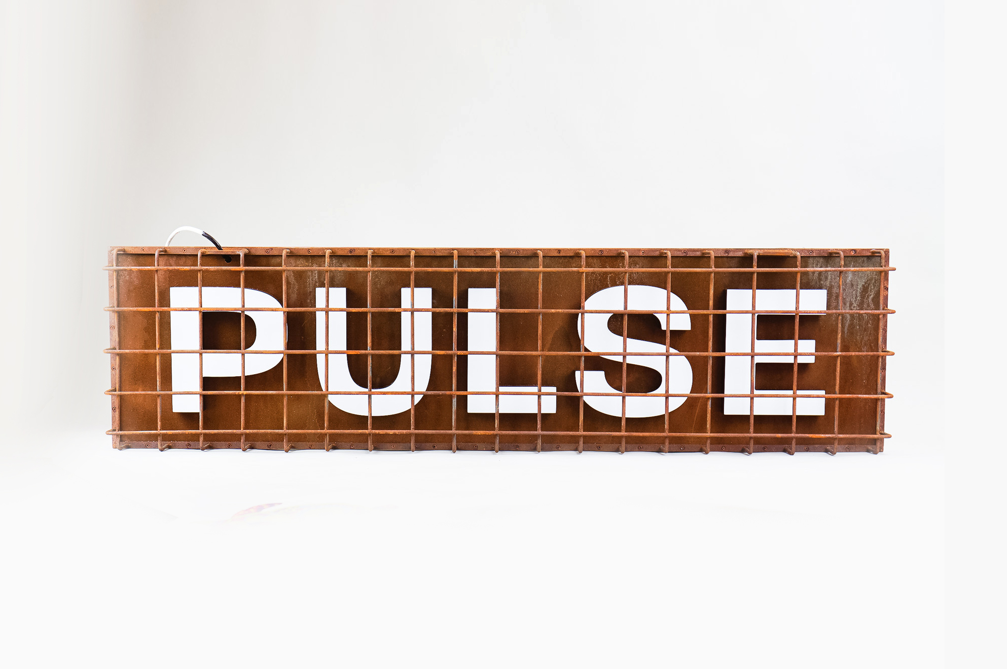 Industrial, caged, rusty metal illuminated sign for Pulse, a fitness studio at Newtown Athletic Club, a premiere family fitness and wellness center serving residents of Newtown, PA