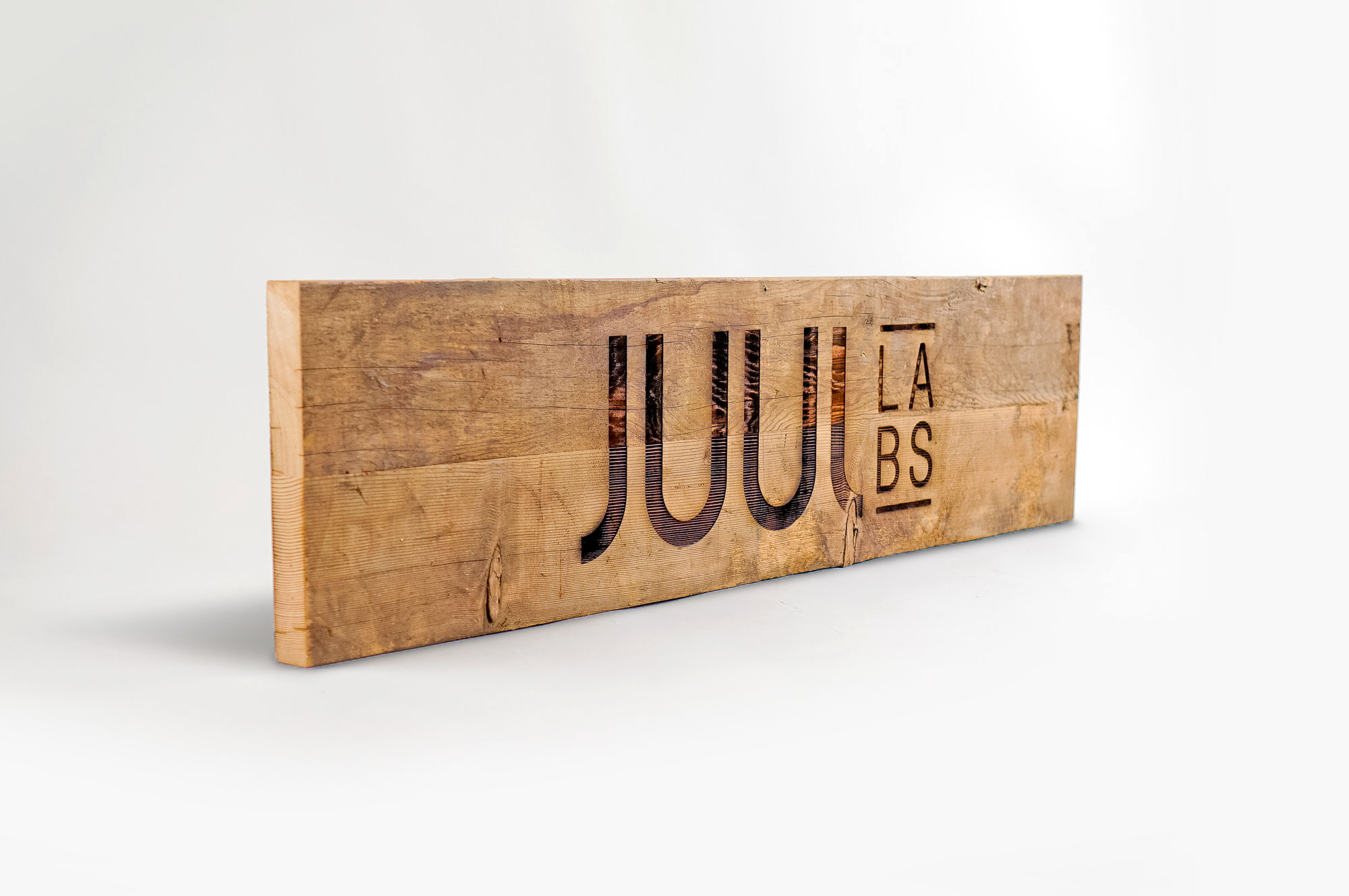 Reclaimed wood sign with etched logo for the San Francisco office of Juul, an electronic cigarette company.