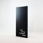 Modern, narrow, banner-like black and white blade sign for The Little Flower Shop, a florist in Larkspur, CA.