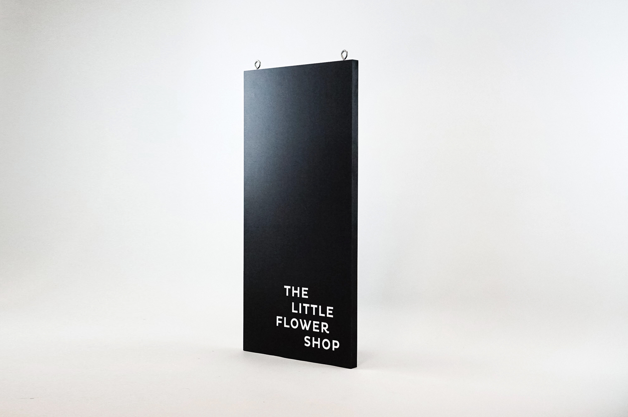 Modern, narrow, banner-like black and white blade sign for The Little Flower Shop, a florist in Larkspur, CA. Modern, narrow, banner-like black and white blade sign for The Little Flower Shop, a florist in Larkspur, CA.