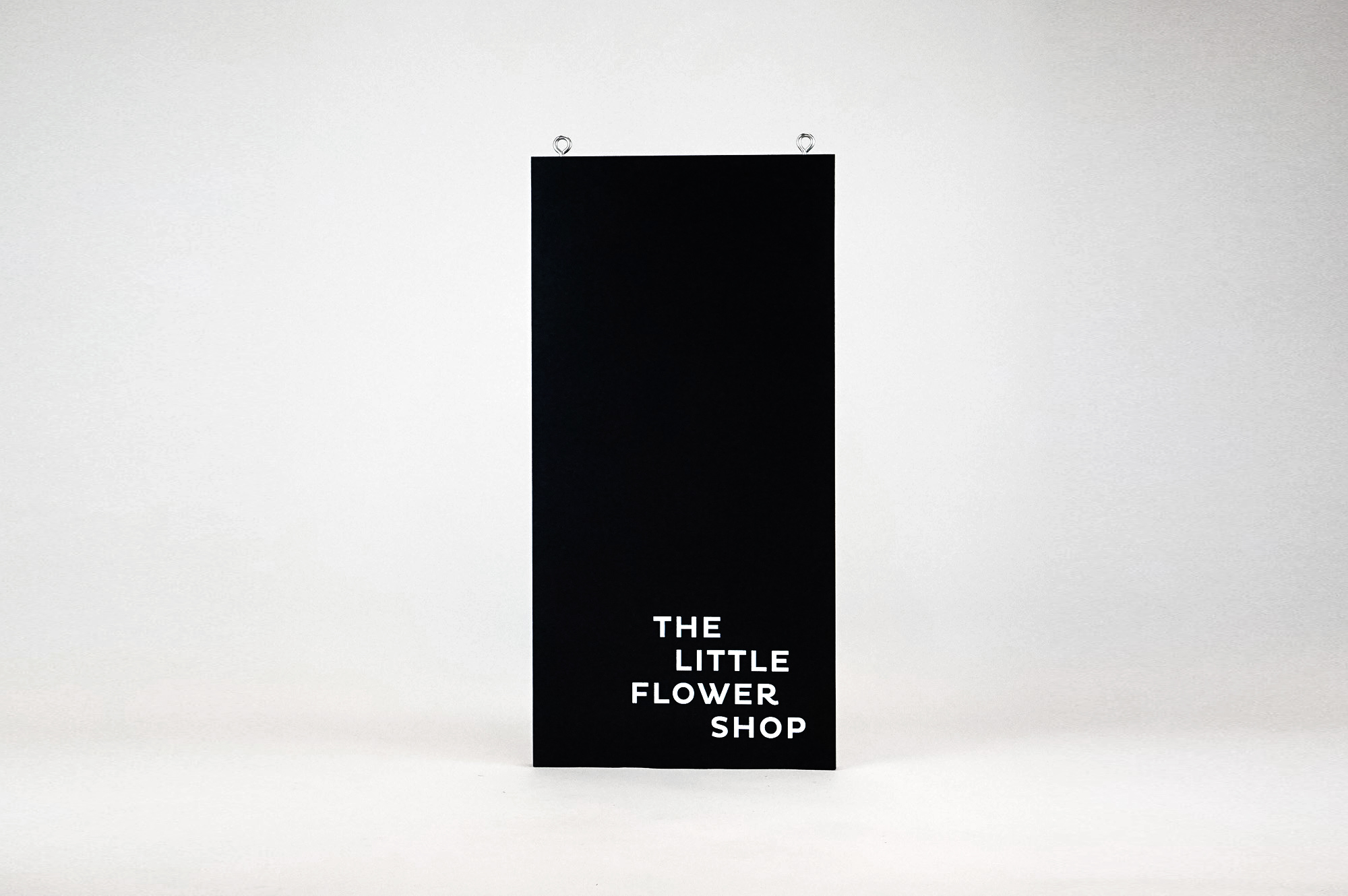 Modern, narrow, banner-like black and white blade sign for The Little Flower Shop, a florist in Larkspur, CA.