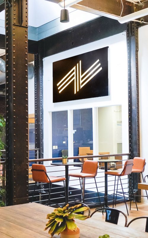 Illuminated black wood sign with warm light on the atrium wall of Zeus, a San Francisco based company providing beautiful, fully furnished homes for business travelers staying one month or longer.