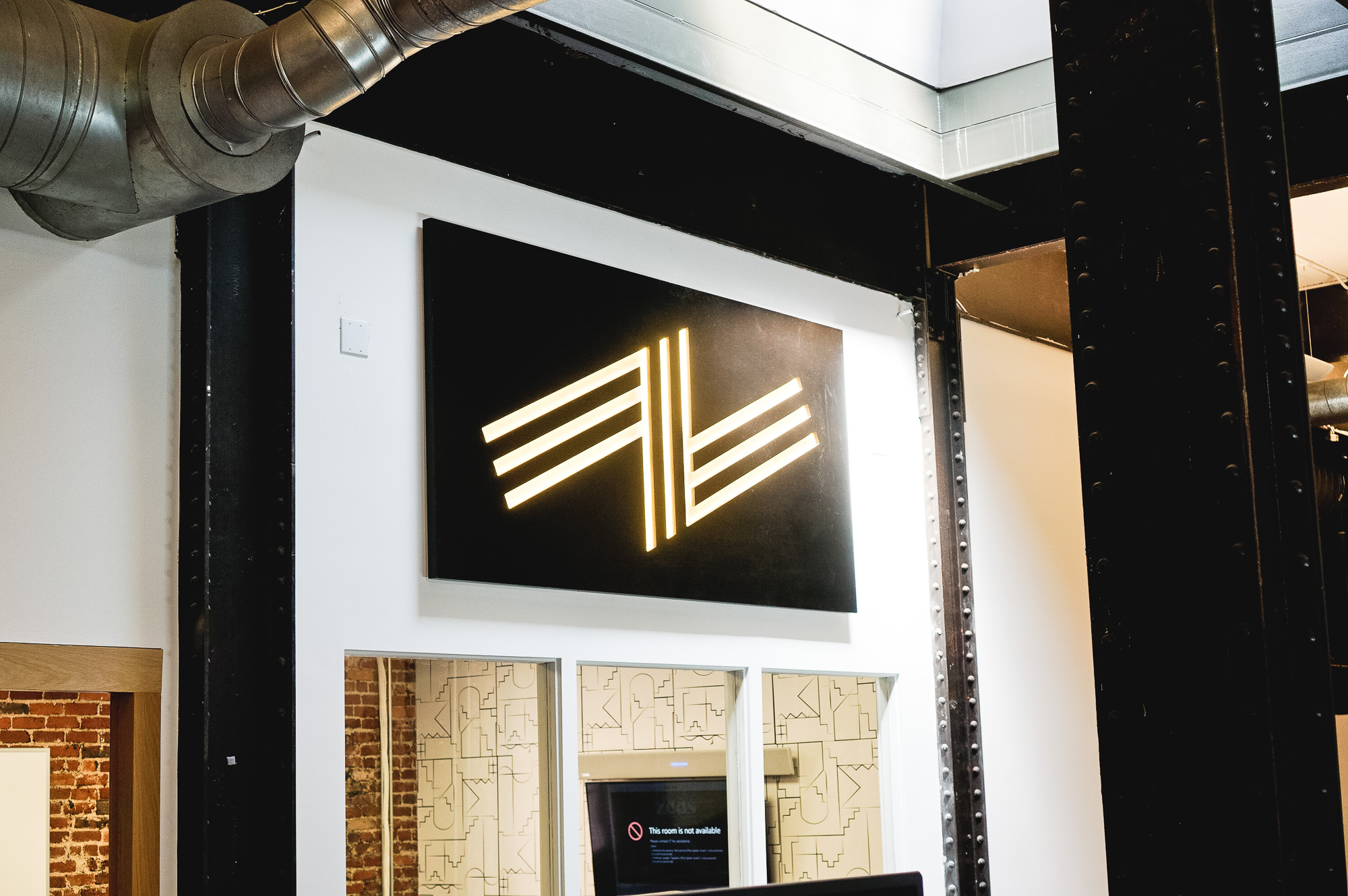 Illuminated black wood sign with warm light on the atrium wall of Zeus, a San Francisco based company providing beautiful, fully furnished homes for business travelers staying one month or longer. Illuminated black wood sign with warm light on the atrium wall of Zeus, a San Francisco based company providing beautiful, fully furnished homes for business travelers staying one month or longer.