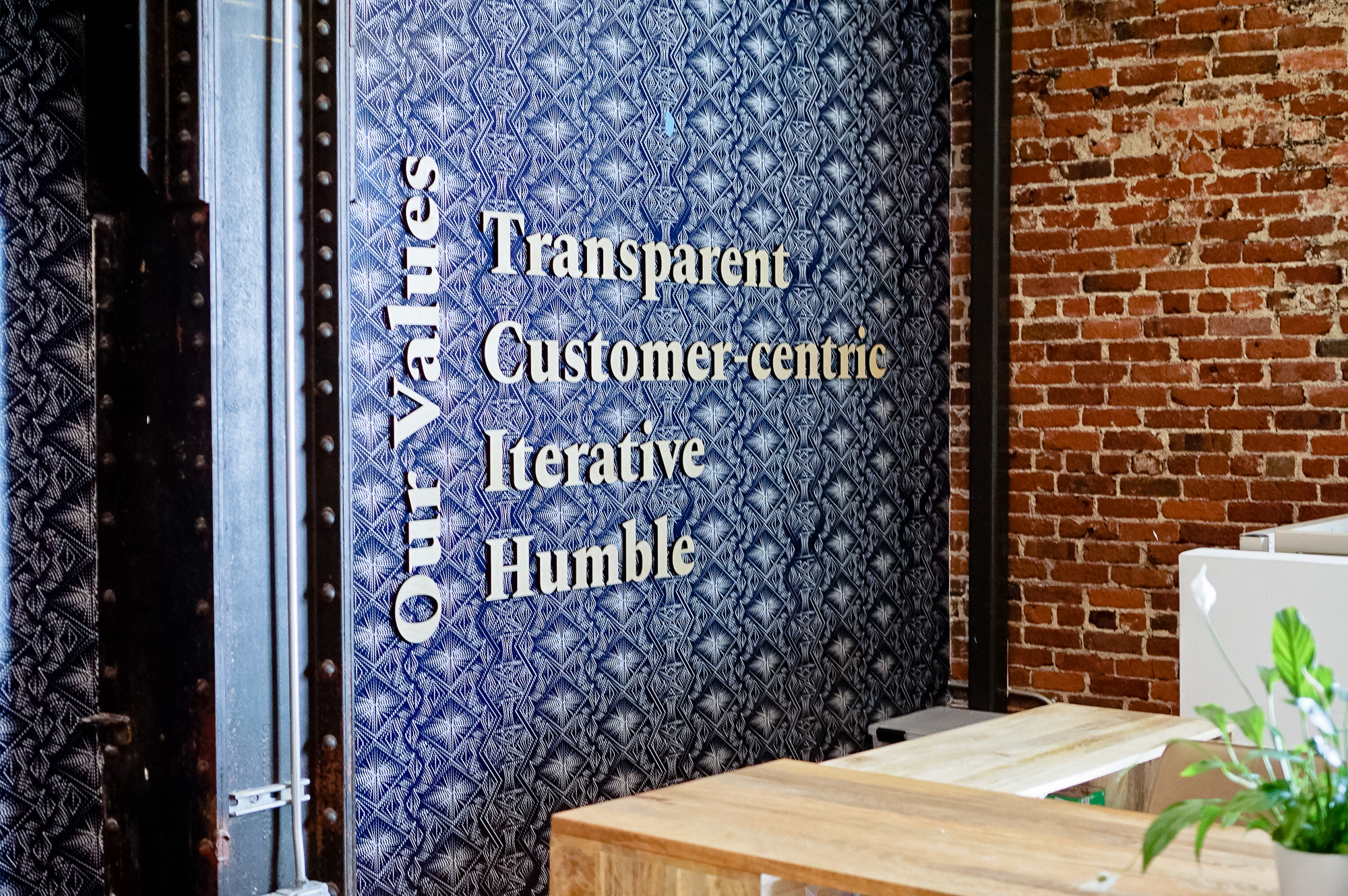 Light wood letters on blue geometric patterned wallpaper for the lobby of Zeus, a San Francisco based company providing beautiful, fully furnished homes for business travelers staying one month or longer.