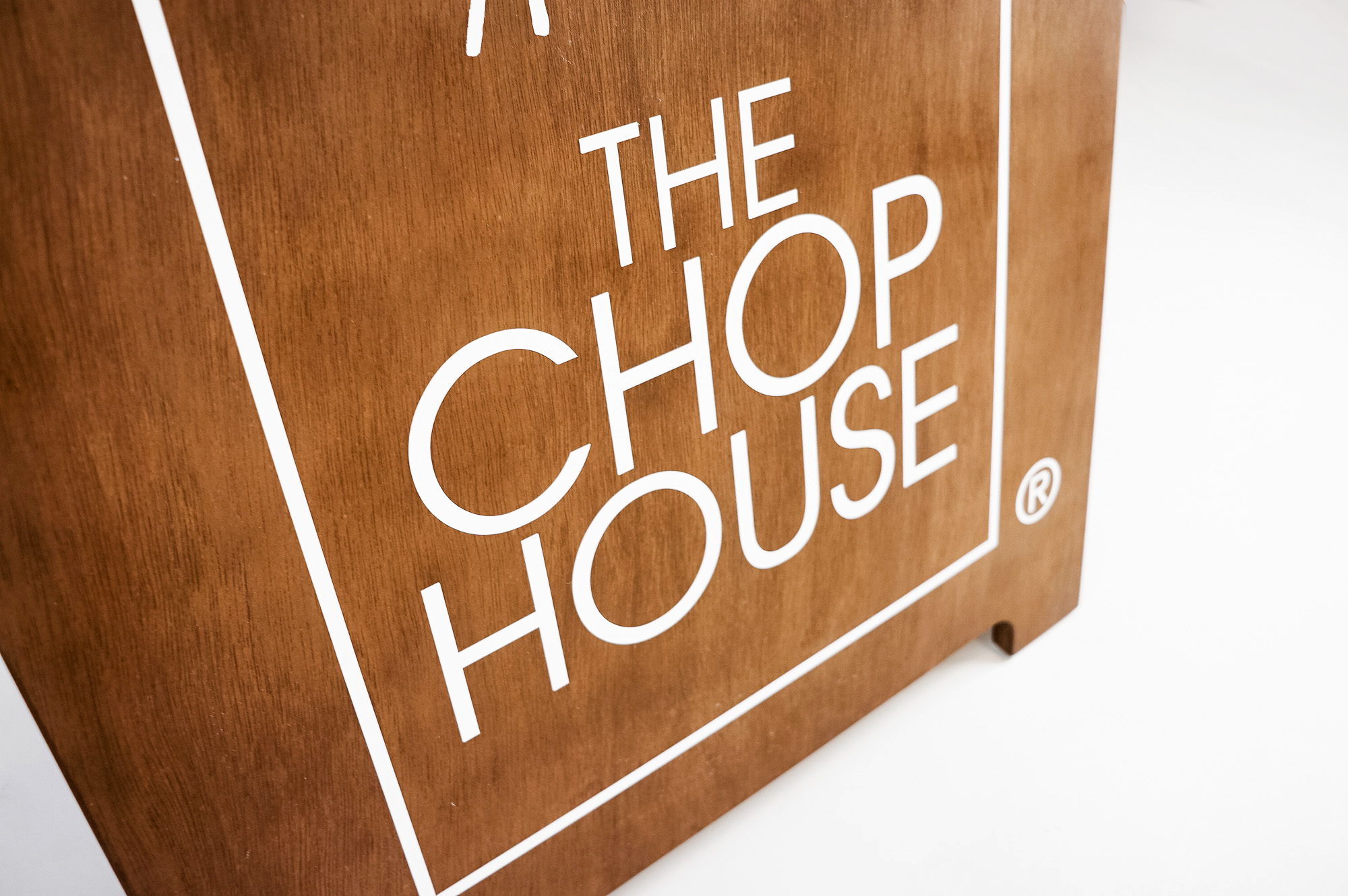 Dark wood sidewalk A-frame sign with white logo for The Chop House, a bar and lounge in Toledo, Ohio.