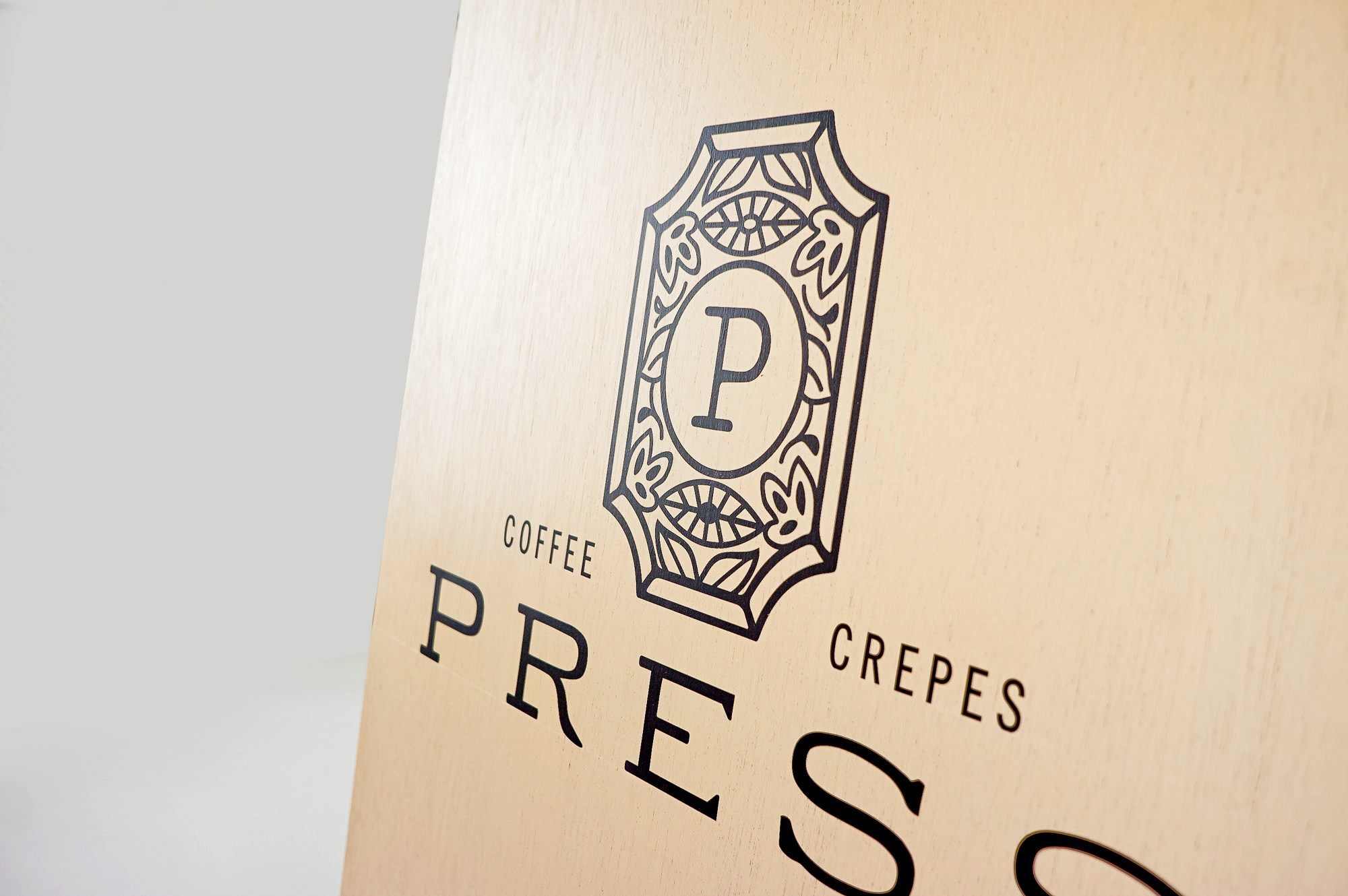 Light wood A-frame sidewalk sign with intricate black logo and text for Press, a European-Inspired coffeehouse and crêperie in downtown Graham, NC. Light wood A-frame sidewalk sign with intricate black logo and text for Press, a European-Inspired coffeehouse and crêperie in downtown Graham, NC.
