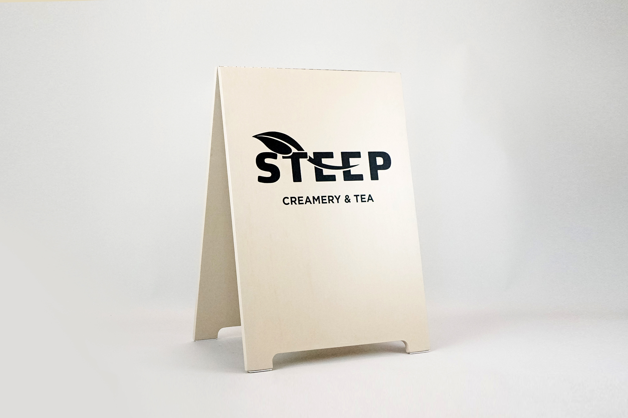 Light wood A-frame sign with black logo for Steep, a cafe in downtown San Francisco. Light wood A-frame sign with black logo for Steep, a cafe in downtown San Francisco.