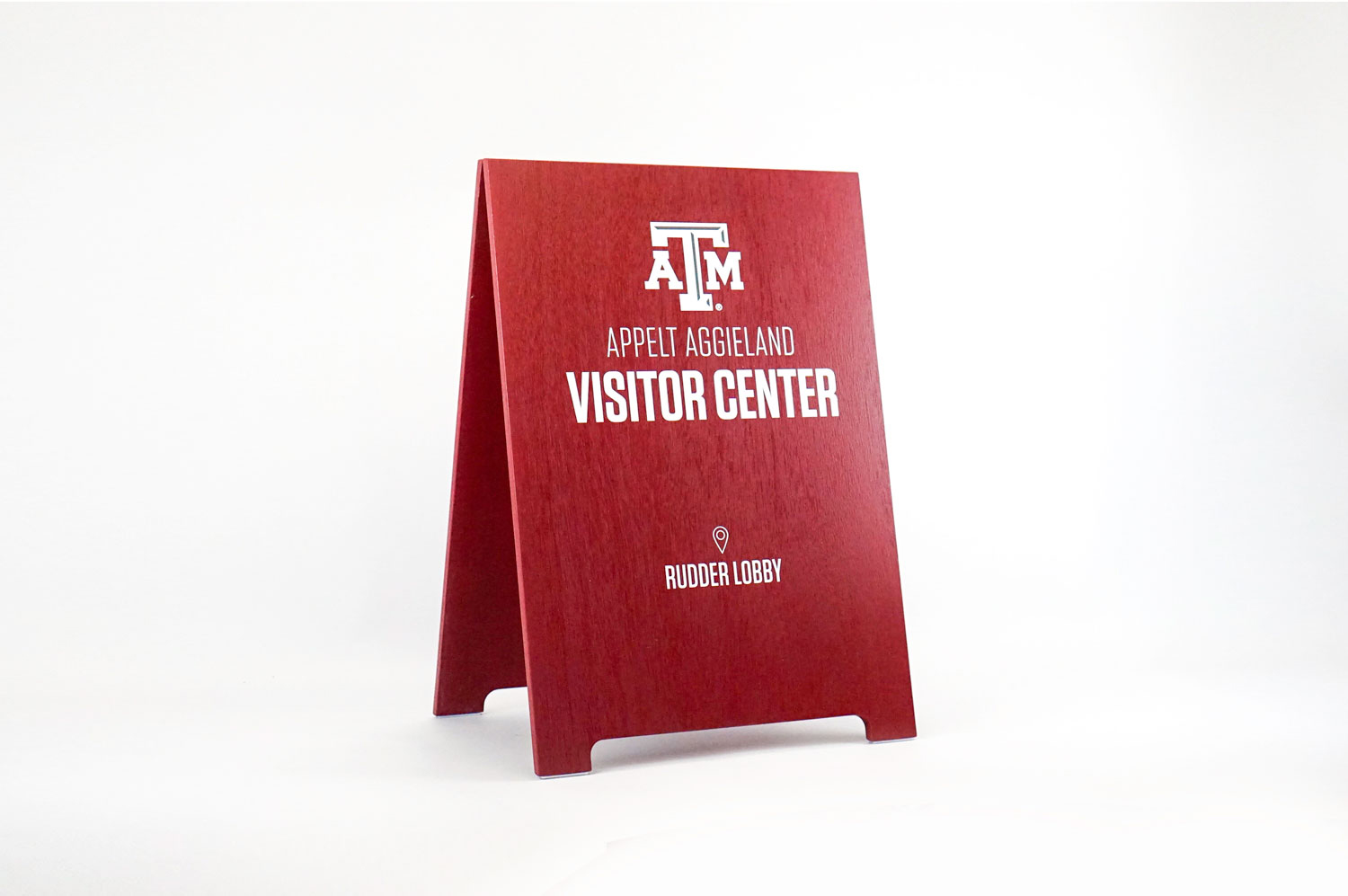 Red A-frame sign with white text for the visitor center at Texas A&M, a public research university in College Station, Texas. Red A-frame sign with white text for the visitor center at Texas A&M, a public research university in College Station, Texas.