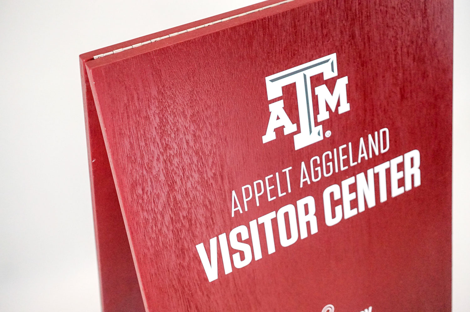 Red A-frame sign with white text for the visitor center at Texas A&M, a public research university in College Station, Texas. Red A-frame sign with white text for the visitor center at Texas A&M, a public research university in College Station, Texas.